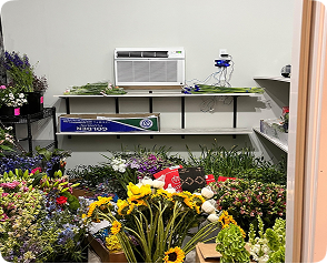 CoolBot walk-in cooler setup surrounded by vibrant flowers and organized shelving, showcasing efficient cooling for florists.