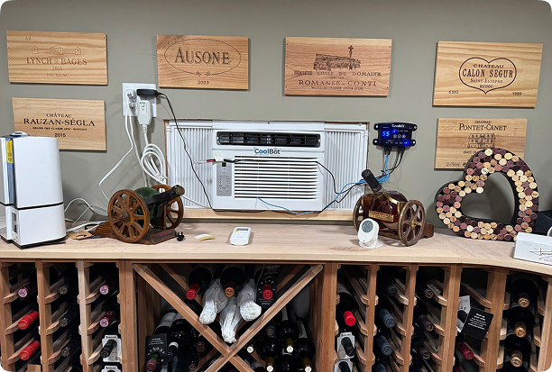 CoolBot air conditioner unit in wine cellar with wine bottles, decorative cork heart, and wooden wine labels on the wall.