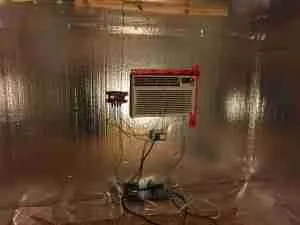 Air conditioner unit installed in a reflective insulated wine cellar, showcasing temperature control setup for DIY wine storage.