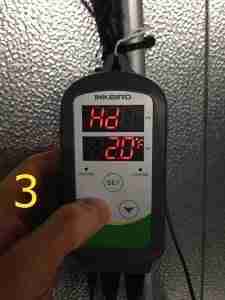 INKBIRD temperature controller displaying HD setting of 2°F and current temperature of 20°F, with hand adjusting settings, relevant to CoolBot winter setup instructions.
